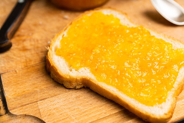 Slice of freshly baked rural bread with homemade citrus jam. Selective focus.
