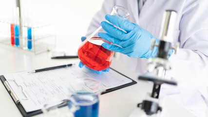 Fototapeta premium Young Asian scientist Working looking through a microscope doing research for analyzing a Experiments sample in a forensic laboratory.