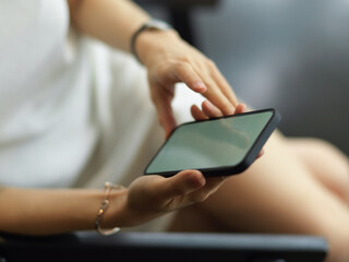 Female hands using smartphone while relaxed sitting on the armchair