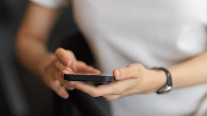 A woman using smartphone in her hands while sitting on the armchair