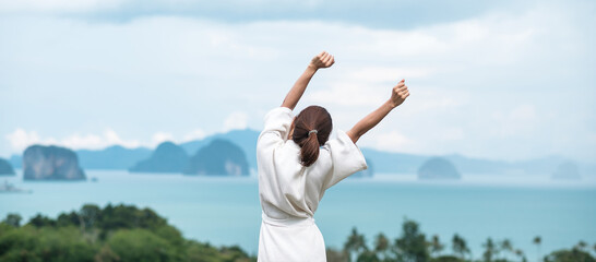 happy woman in bathrobe stretching after waking up and enjoy Ocean view, Tourist relaxing in...