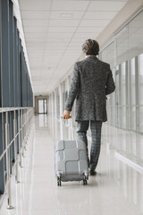 Senior businessman with travel suitcase in airport