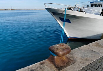 Bitta con gomena azzurra sul mare blu e barca bianca attraccata