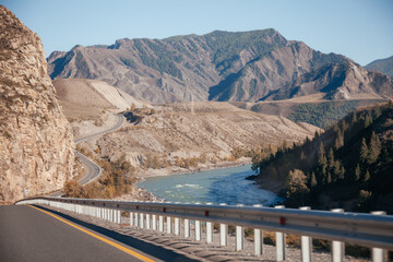 Road Chuya tract in Altai Mountains with river on the side, Siberia, Russia.