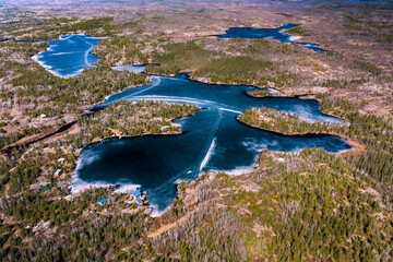 Ice melting on a lake in the middle of the Canadian shield.  Lots of boreal forest surrounding.  Ice roads still visible from this top down shot of the ice.