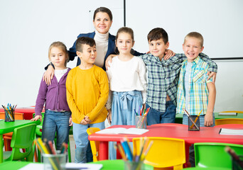Friendly group of pupils with female teacher in schoolroom. High quality photo