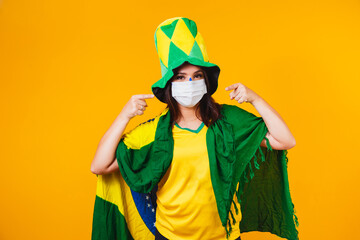 Brazilian woman with the Brazilian flag wearing a virus protection mask, celebrating, screaming and...