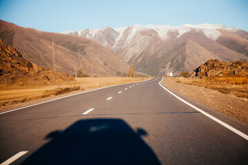 Chuya tract road with shadow of car with snow peaks of Altay Mountain on background