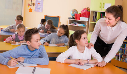 Woman teacher helping to pupils at lesson in classroom