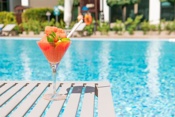 Fototapeta na wymiar Fresh red cocktail with ice in glass on swimming pool. Tropical juice on luxury vacations. Concept summer holiday and travel