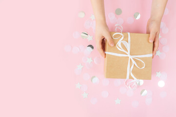 Hands holding paper gift box with ribbon, star, circle paper confetti, glitters