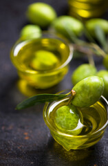 Olive oil and olive branch on black background