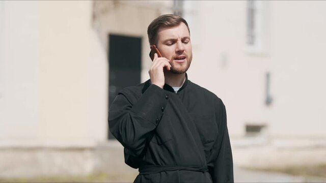 A nice young priest is talking on the phone