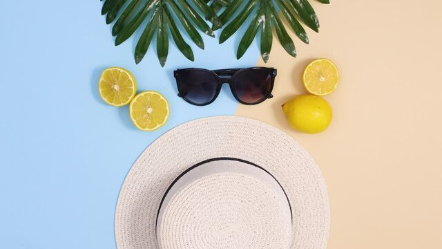 Summer vacation concept stop motion flat lay. Summer hat and sunglasses move with lemons and tropic leaves 