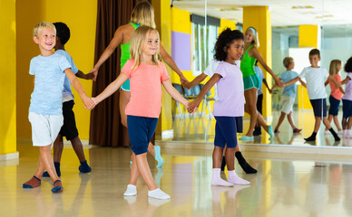 Happy kids and female teacher dancing together in studio at elementary school. High quality photo