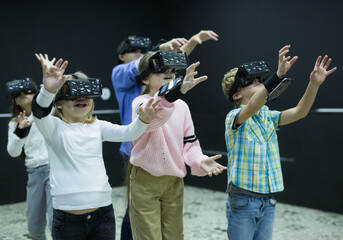 Enthusiastic glad smiling children in virtual reality glasses in quest room
