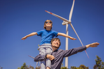 Alternative energy, wind farm and happy time with your family. Happy father carrying his son on...