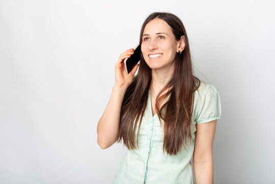 Photo Of Young Charming Woman Smiling And Talking On Phone Near White Background