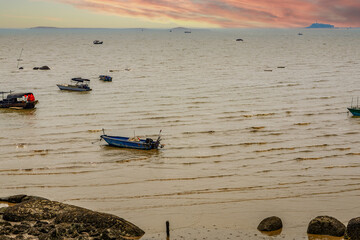 The beach and fishing boats docked near the sea under the sunset