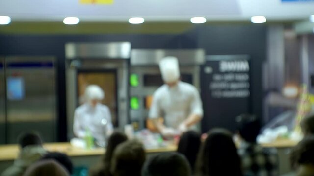 Modern business product presentation. Chefs conduct a master class in front of the assembled audience. Blurred background for a culinary or business theme.