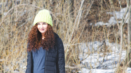 red-haired curly girl in a hat smiling