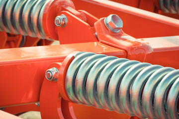 Big and hard steel silver spring as part and detail of red industrial or agricultural machine