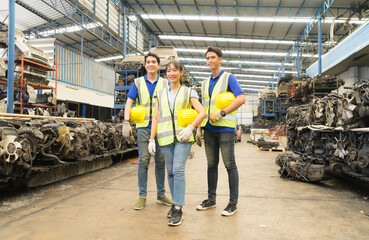 Fototapeta premium Woman and men work together, they hold helmets and look at same way. Asian engineer worker woman and man show teamwork by holding helmets and looking at same way in factory-warehouse