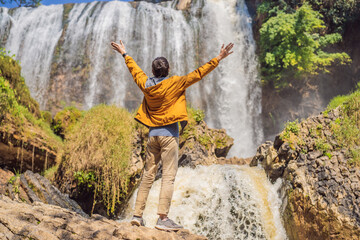 Fototapeta premium Male tourist on the background of Elephant waterfall near Dalat city in Vietnam
