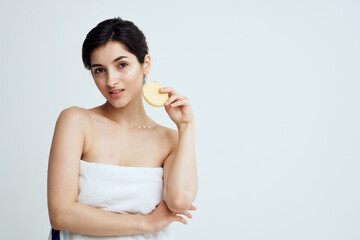 Beautiful brunette with a sponge in her hands white towels clean skin care