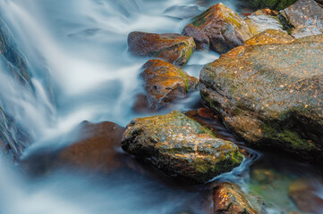 Streams of water over stones and autumn leaves Ularsky waterfall