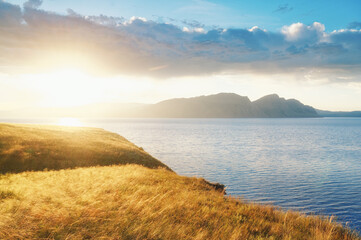 Sunrise over the Krasnoyarsk sea in Khakassia Tepsey and Oglakhty mountains autumn yellow foliage in the rays of the sun water and clouds in the sky