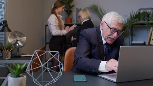 Cunning senior professional businessman grandfather company director rubbing hands, waiting for money income. Elderly mature man scheming evil tricky prank plan in mind, smiling in office interior