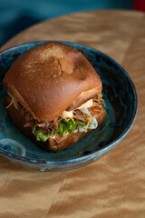 delicious burger with cheese and onions on a blue background and in a blue plate on a wooden table