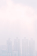 Cityscape in the mist, tall building in thick mist, uncleared or blurred image view, vertical image with blank space area for copy and design.