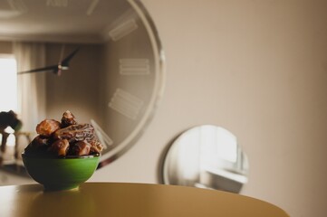 green palm bowl on the table and mirrored clock on the background