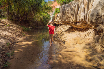 Boy tourist on the Fairy stream among the red dunes, Muine, Vietnam. Vietnam opens borders after...