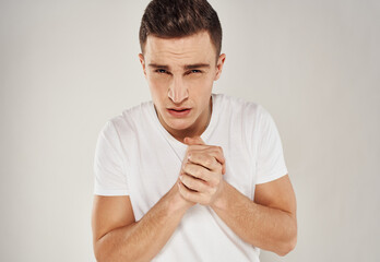Guy in a white T-shirt sadness emotions model light background gesticulate with his hands