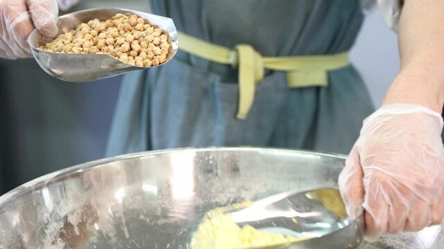 He pours the white flour into a silver cup. Chickpea flour