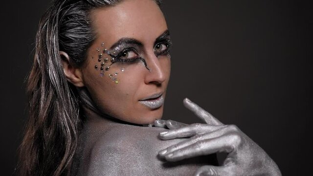 Close-up portrait of beautiful woman with silver body art.
