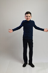 Teen boy in full growth in dark clothes on a white background