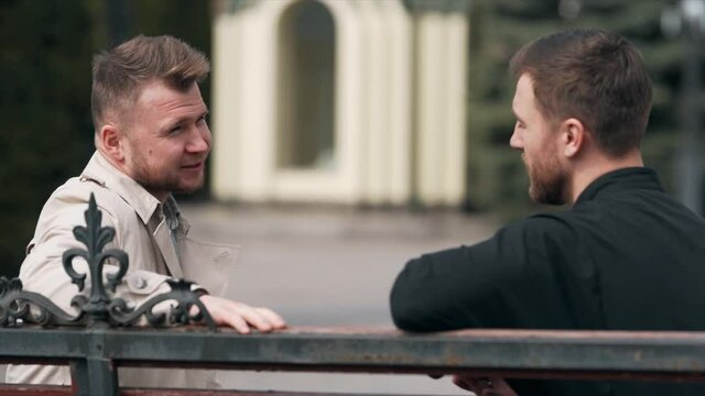 Young man sitting on a bench with a priest communicates