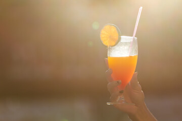 hand holding a cocktail with an orange in glass