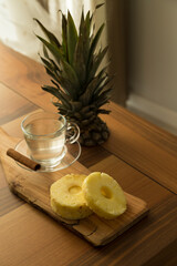 A glass of pineapple tea with cinnamon stick on the wooden service for food stylist concept.