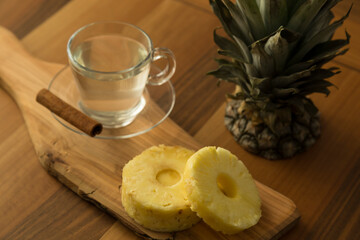 A glass of pineapple tea with cinnamon stick on the wooden service for food stylist concept.