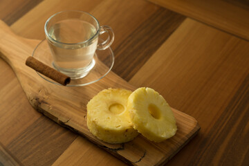A glass of pineapple tea with cinnamon stick on the wooden service for food stylist concept.