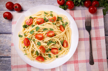 Pasta spaghetti with cherry tomatoes and parsley on a light background.