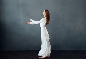 Fototapeta na wymiar Charming lady in a white dress on a gray background dance gesticulating with her hands Copy Space model