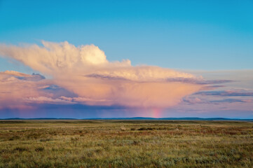 Thundercloud at sunset with streams of rain and a rainbow from the sun, Fields after rain, evening in Khakassia