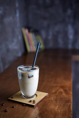 Ice coffee in a tall glass with cream poured over and coffee beans. Cold summer drink on a cafe...