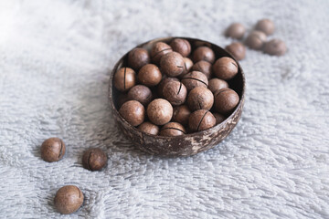 Macadamia nuts in a plate on a gray background. Different textures: plaid, nuts, shells